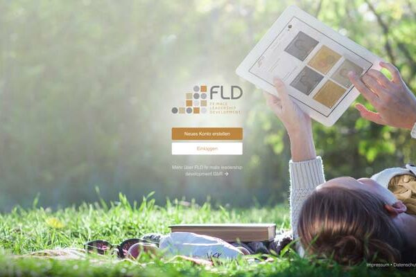 Frau liegt mit einem Tablet im Gras und loggt sich in den FLD Online Campus ein