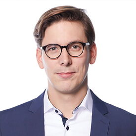 Mann mit Brille im Anzug vor weißem Hintergrund